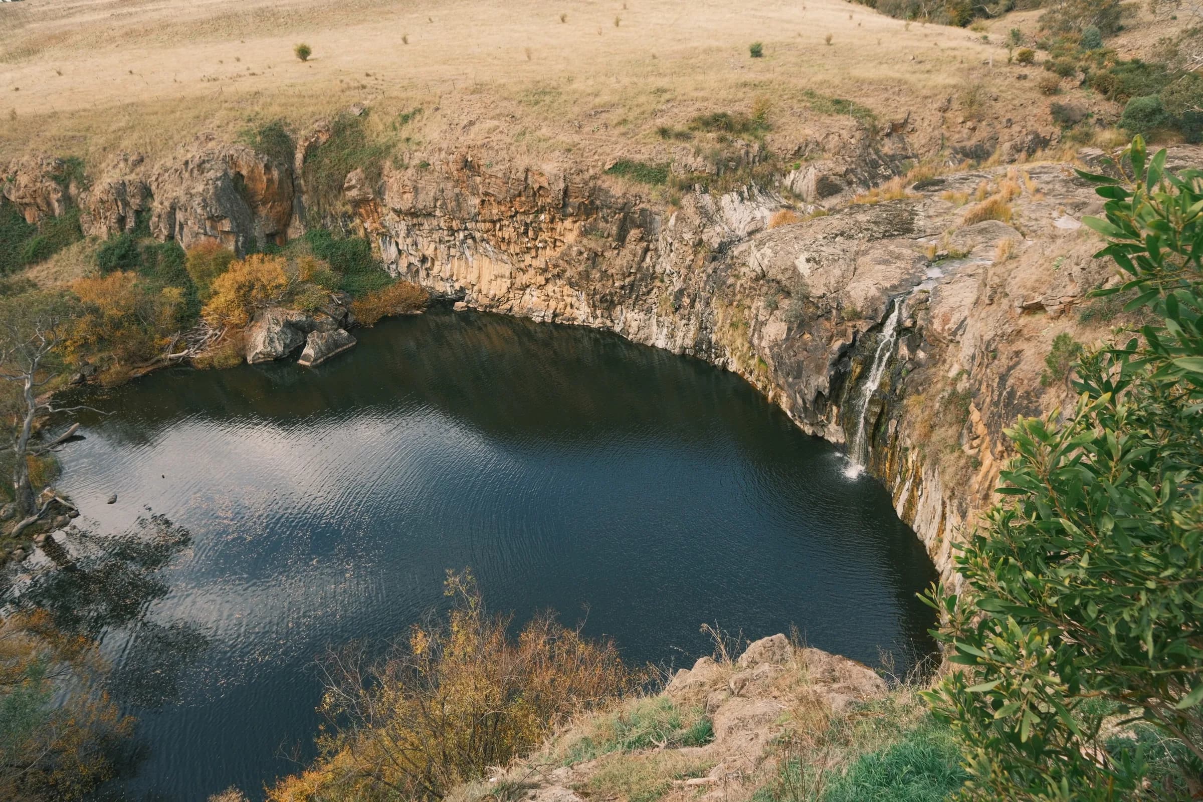 A still waterhole ringed by a tall rock rim