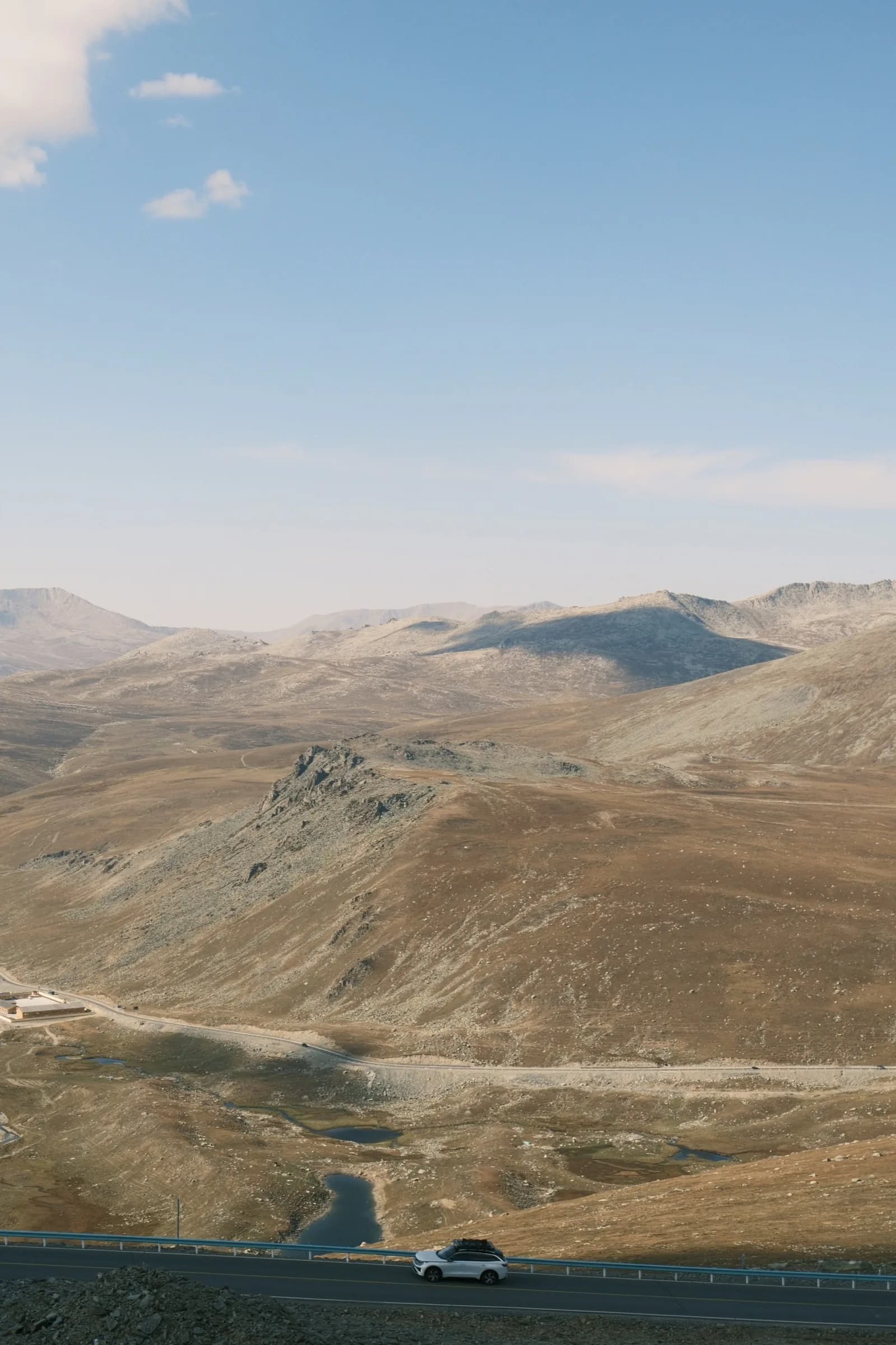 A car driving along a highway through an arid mountain pass