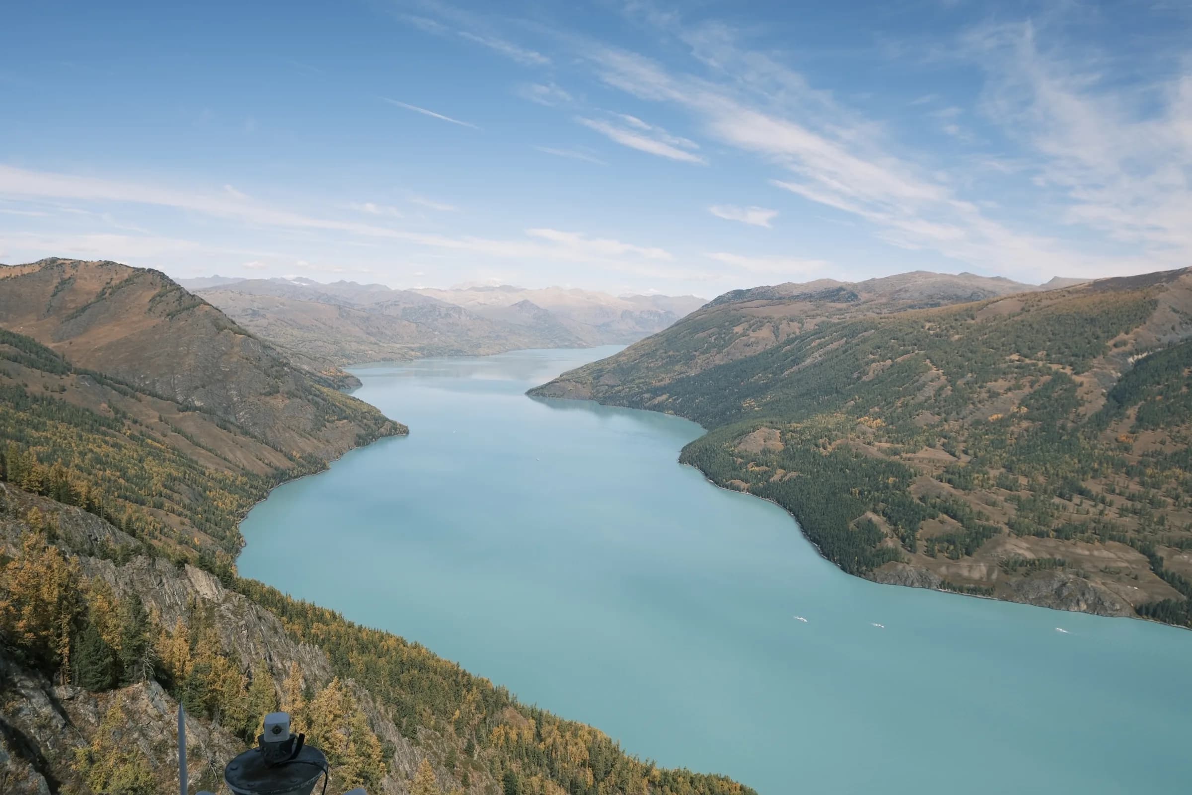 A turquoise river bending through a valley of layered ridges