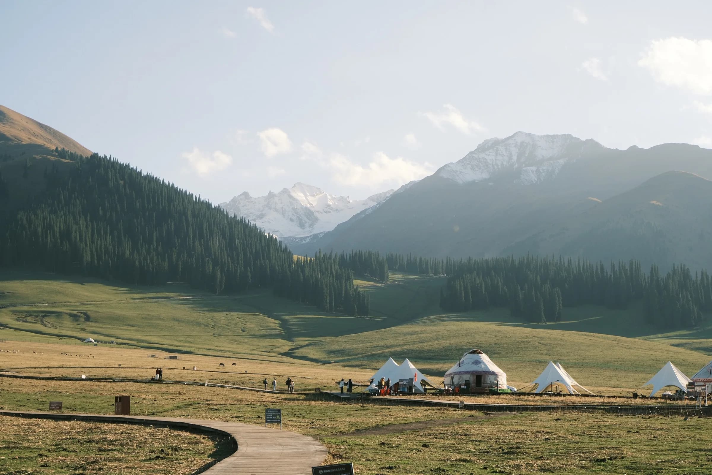 White yurts and tents scattered across a green valley