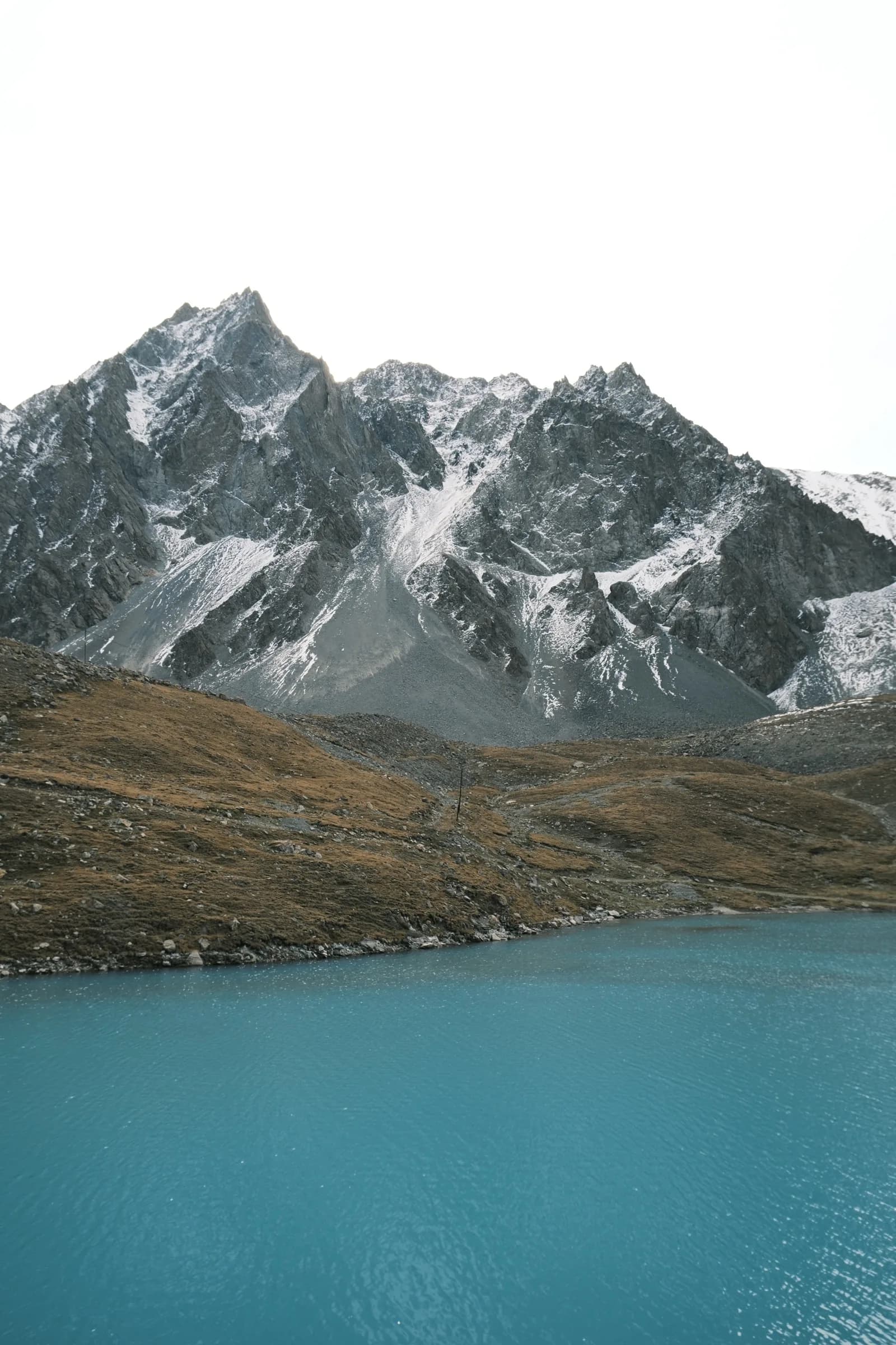 Turquoise alpine lake beneath a snow-streaked mountain