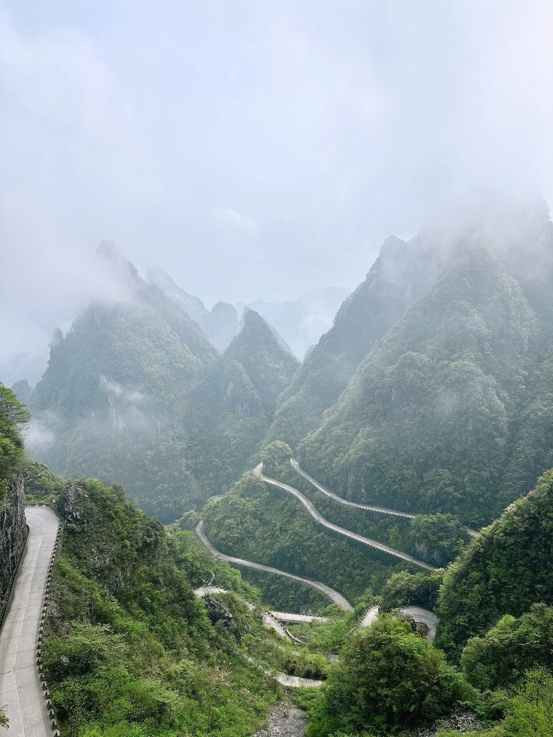 A road and a stone staircase winding through steep green slopes