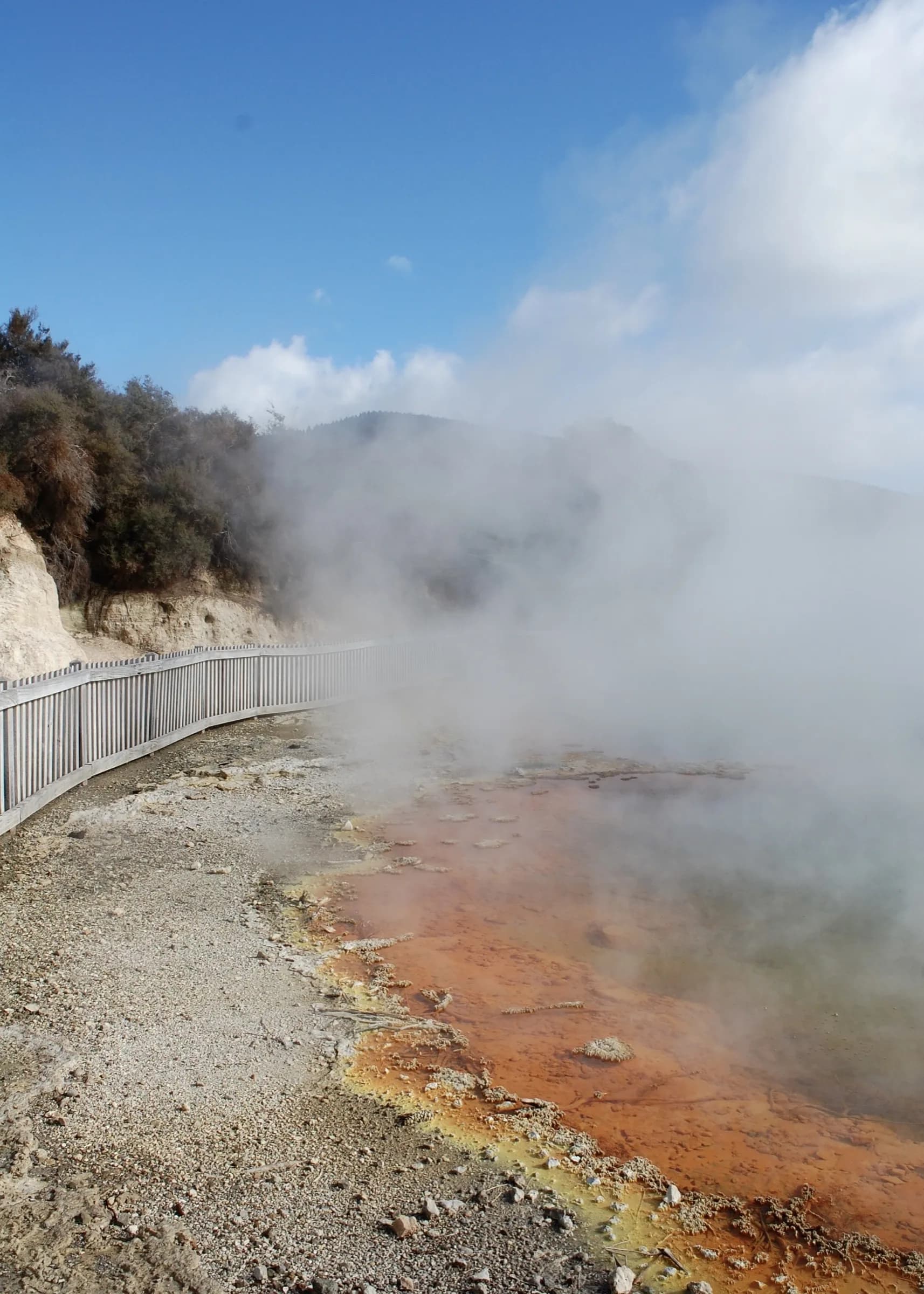 Orange mineral terraces steaming beside a gravel path