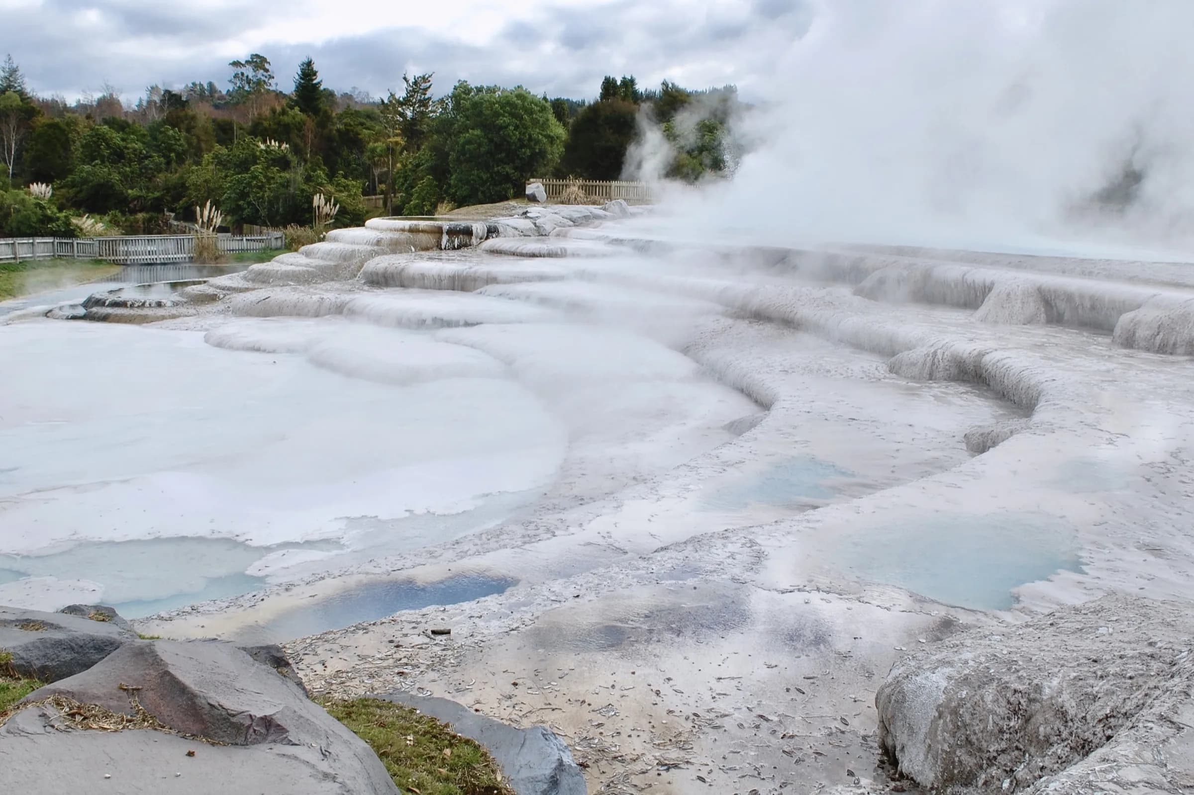 Steam sweeping across bare white terraces with shallow pools