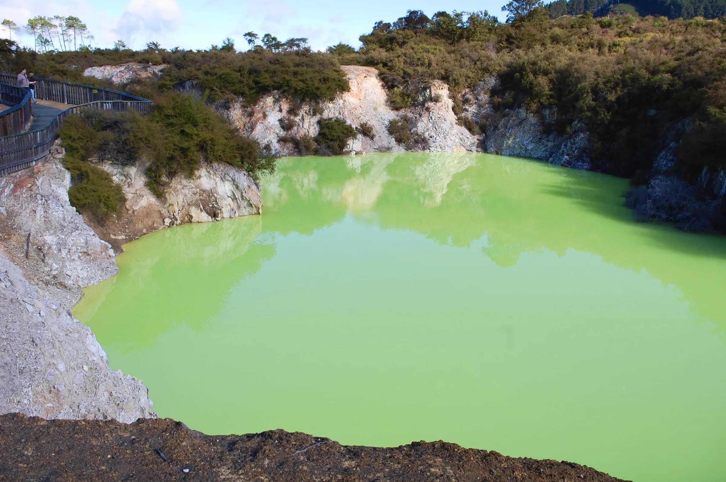 Boardwalk above a crater pool of vivid green water